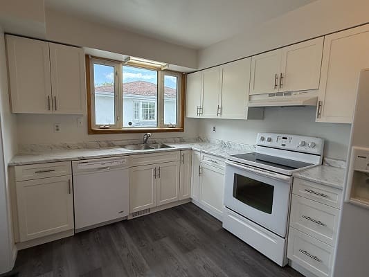 Modern kitchen with white cabinets and appliances.