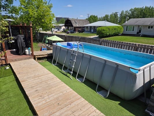 Backyard above-ground pool with wooden deck.