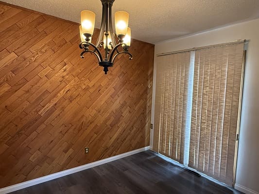 Dining room with chandelier and wooden wall.