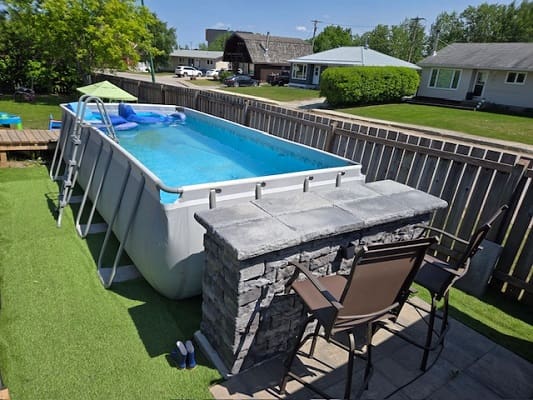 Backyard pool with bar and chairs.