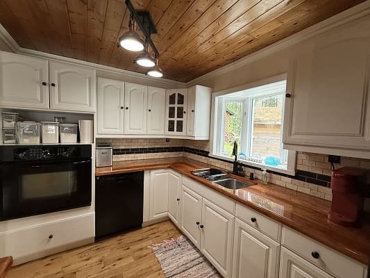 Rustic kitchen with wooden ceiling and cabinets.
