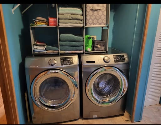 Laundry room with washer, dryer, and shelves.