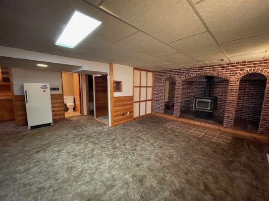 Basement room with fireplace and carpet flooring.