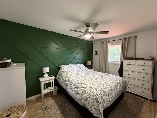 Bedroom with green accent wall and bed.