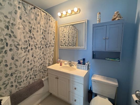 Small blue bathroom with shower and vanity.