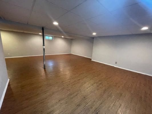 Spacious empty basement with wooden flooring.