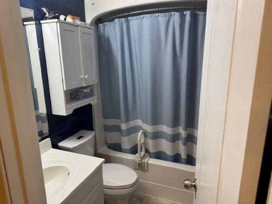 Small bathroom with blue shower curtain.