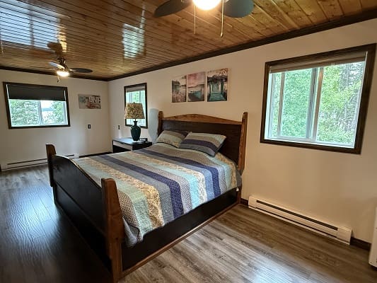 Bedroom with wooden ceiling and large window.