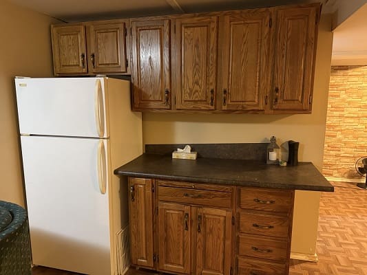 Wooden kitchen cabinets with refrigerator and countertop.