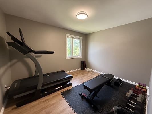Home gym with treadmill and weights.