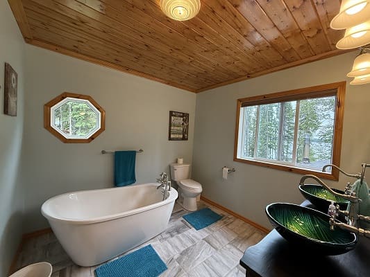 Modern bathroom with wooden ceiling and tub.
