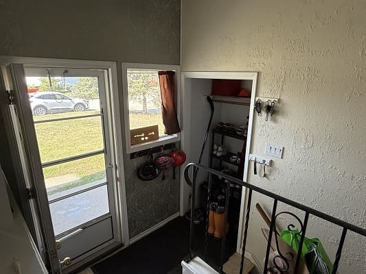 Home entryway with stairs and gardening tools.
