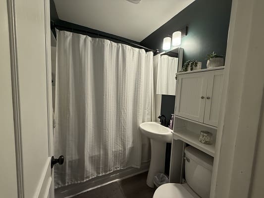 Small bathroom with white shower curtain.