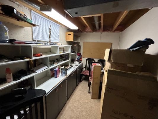 Cluttered storage room with shelves and boxes.