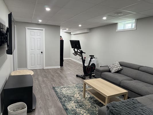 Basement with exercise bike and gray couch.