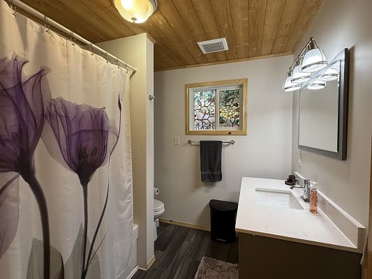 Bathroom with floral curtain and wooden ceiling.