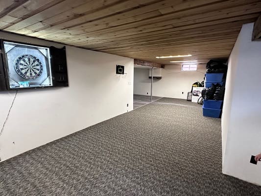 Basement with dartboard and storage bins.