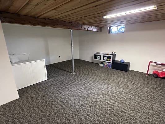Basement playroom with toys and carpeted floor.