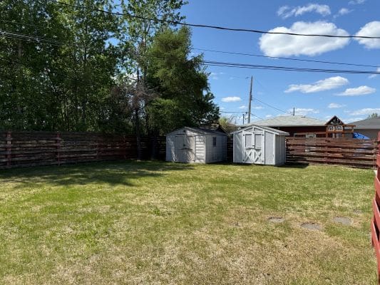 Backyard with sheds and wooden fence.