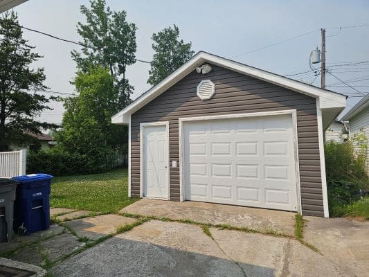 Small detached garage with white door.