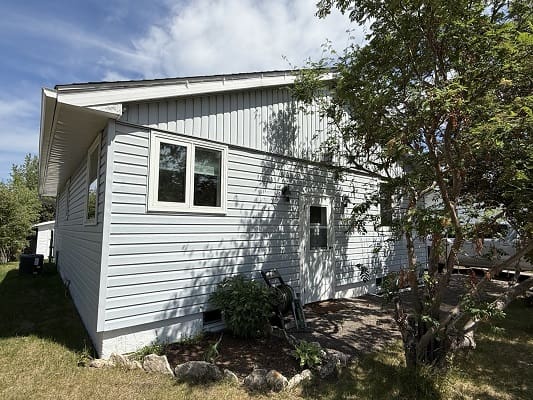 House with white siding and trees outside.