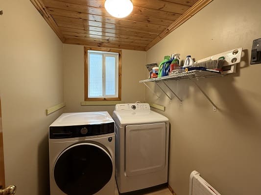 Laundry room with washer, dryer, and shelves.