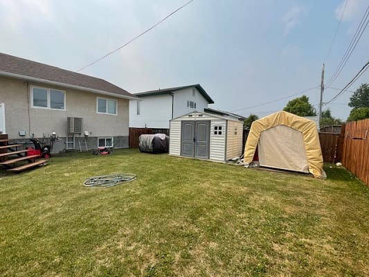 Suburban backyard with shed and tarp shelter.