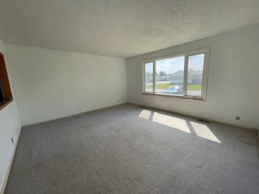 Empty room with large window and carpet.