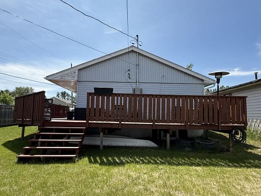 Backyard wooden deck with stairs and railing.
