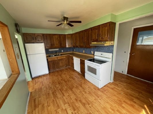 Kitchen with wooden cabinets and white appliances.