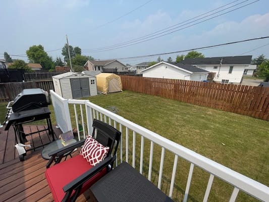 Backyard with deck, chairs, and grill.