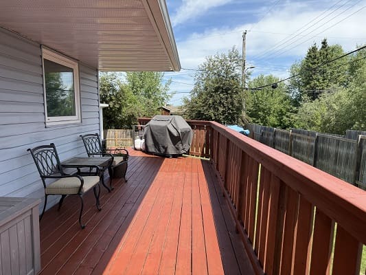 Wooden deck with chairs and a grill.
