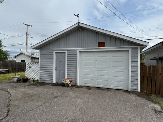 Gray garage with white door and driveway.
