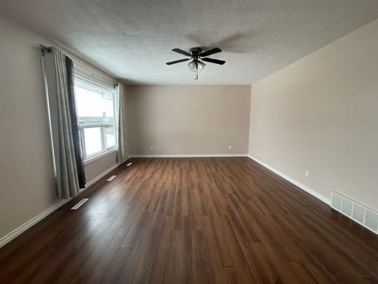 Empty room with wooden floor and ceiling fan.