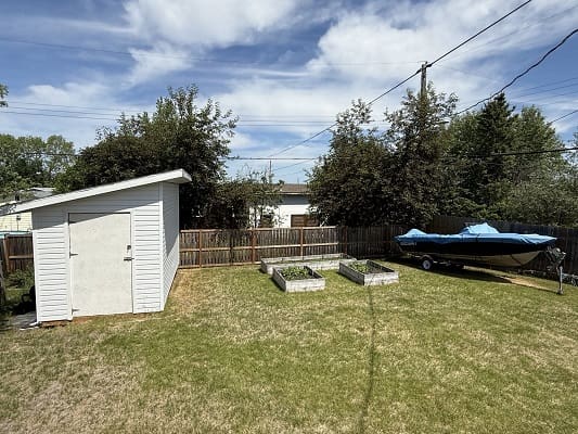 Backyard with shed, planter boxes, and boat.