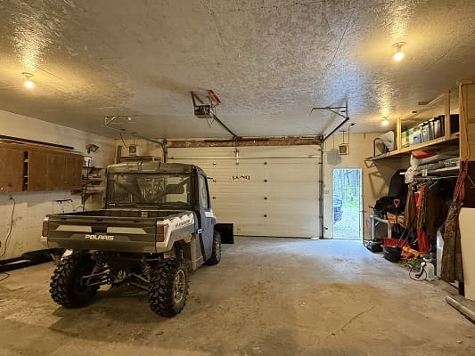 Garage with off-road vehicle and storage shelves.