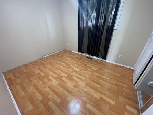 Empty room with wooden floor and curtains.