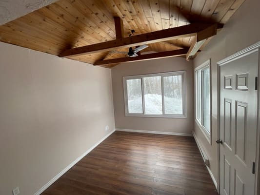 Room with wooden ceiling and hardwood floor.