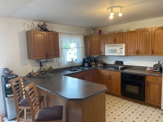 Wooden kitchen with bar stools and appliances.
