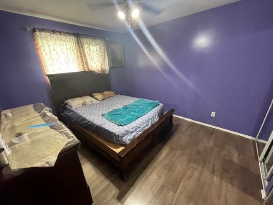 Bedroom with purple walls and wooden floor.