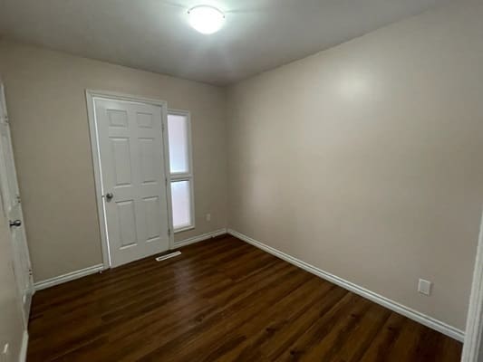 Empty room with wooden floor and door.