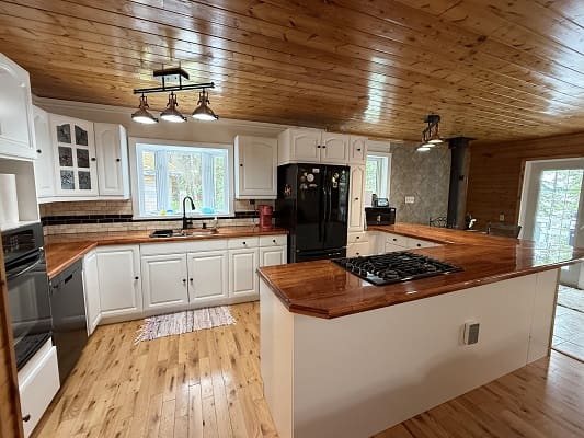 Modern kitchen with wooden ceiling and countertops.