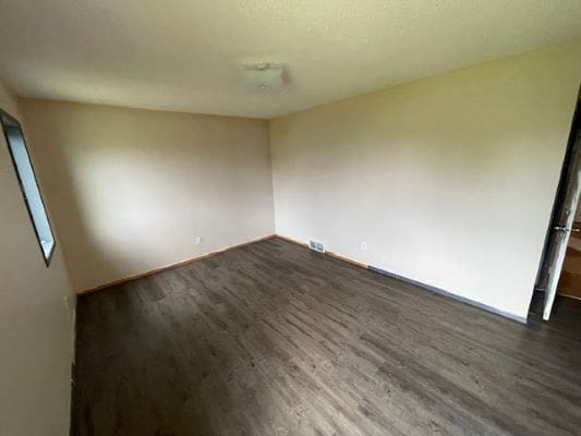 Empty room with dark wood flooring.