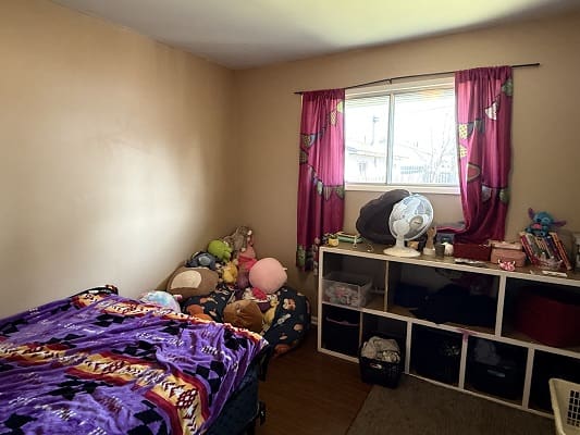 Bedroom with colorful bedding and stuffed animals.