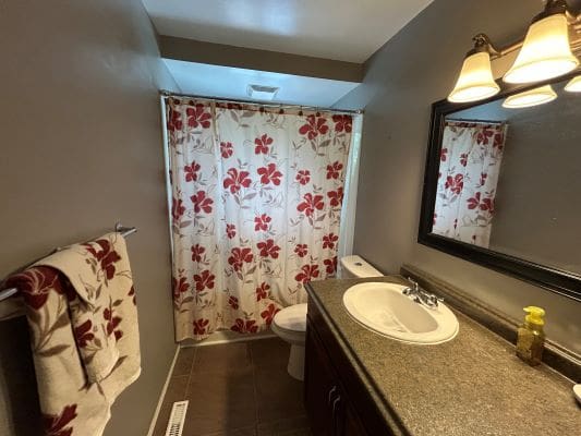 Small bathroom with floral shower curtain.