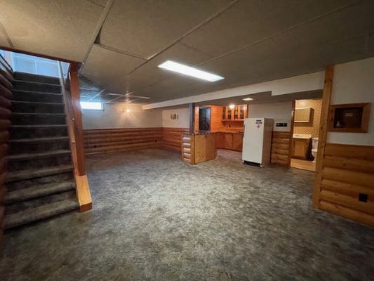 Rustic basement with staircase and kitchenette.