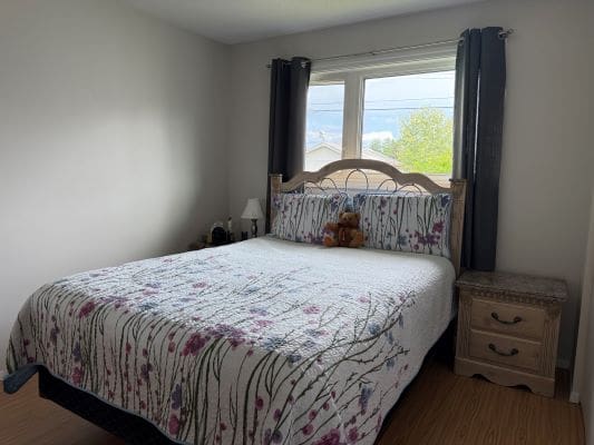 Cozy bedroom with floral bedspread and window.