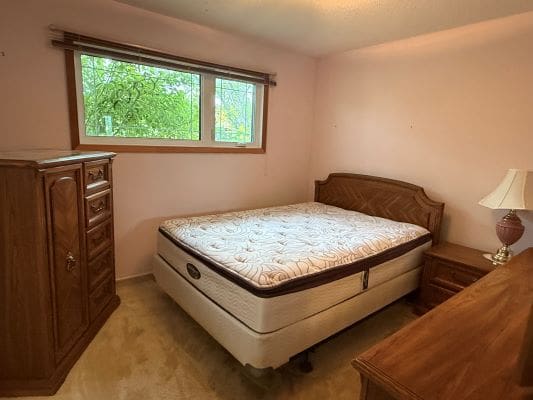 Bedroom with bed and wooden furniture.