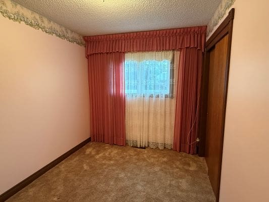 Room with pink curtains and beige carpet.