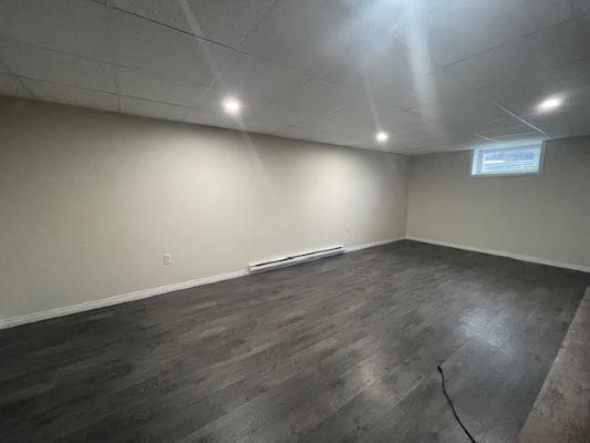 Empty basement with dark wooden flooring.